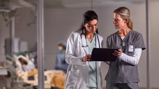 Two healthcare professionals look at a tablet