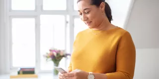 A woman looks at her mobile device in a well-lit living room
