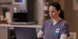 Healthcare professional sitting at table on laptop