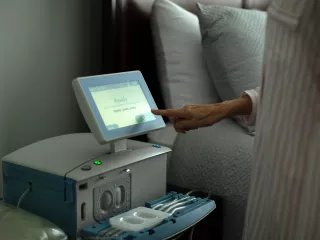 A woman uses the touchscreen of her Amia device on her bedside table