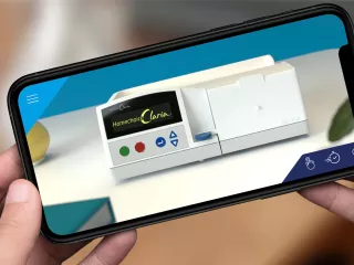 A phone screen shows a video of the Homechoice Claris APD System