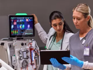 Two healthcare professionals by a PrisMax device