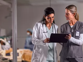 Two healthcare professionals look at a tablet